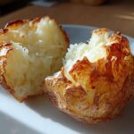 A perfectly cooked air fryer baked potato split in half showing fluffy white interior and crispy brown skin.
