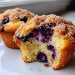 A close-up of a delicious blueberry muffin cut in half showing moist interior and bursting blueberries, topped with cinnamon sugar.