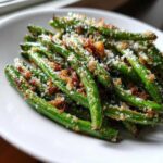 Close-up of roasted green beans topped with crispy brown bits and grated cheese.