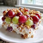 A serving of creamy grape salad topped with red and green grapes and chopped pecans, resembling the chicken salad chick grape salad.