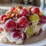 A close-up serving of creamy grape salad, featuring red and green grapes mixed with pecans, similar to chicken salad chick grape salad.