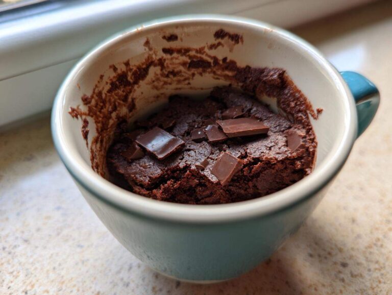 Guiltless 1-Minute Cottage Cheese Microwave Brownie Close-up of a rich, dark chocolate Cottage Cheese Microwave Brownie topped with chocolate chunks inside a light blue mug.