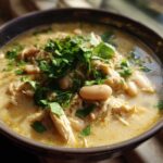 Close-up of a hearty bowl of crockpot white chicken chili, topped with fresh cilantro.