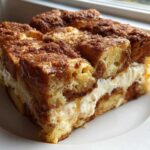 A thick, square slice of overnight french toast casserole with a creamy filling and cinnamon topping.