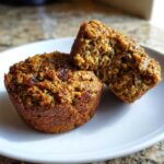 Close-up of two moist bran muffins, one cut in half showing the texture and raisins.
