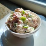 Close-up of creamy ham salad with chunks of ham and green bell pepper in a small white bowl.