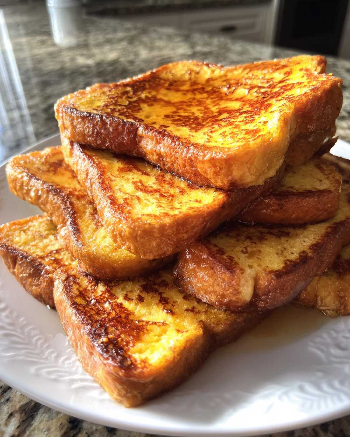 A tall stack of golden brown, perfectly cooked easy french toast slices resting on a white plate.