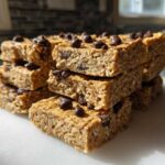 A stack of homemade, chewy protein bars topped with mini chocolate chips, ready to eat.