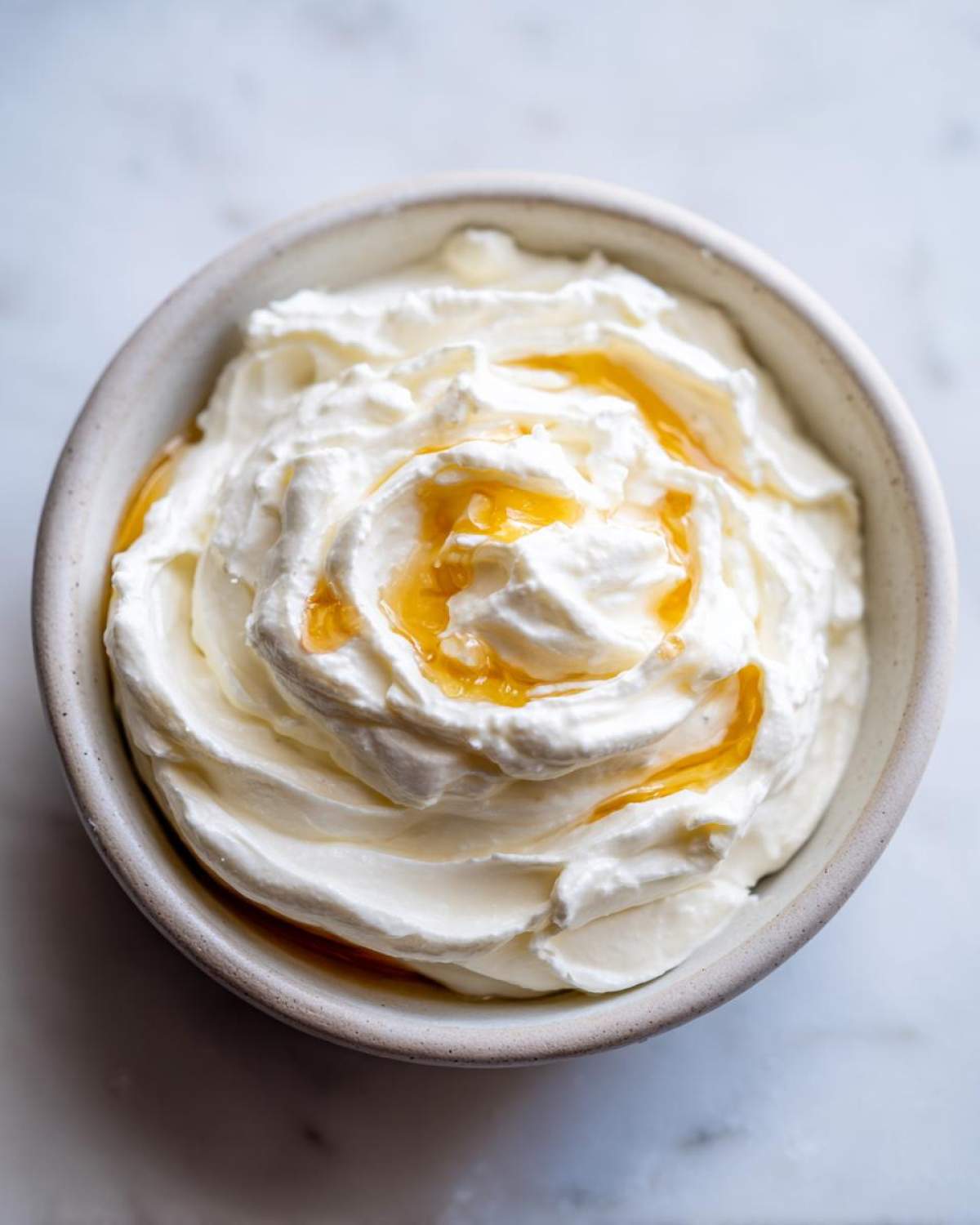 Overhead view of creamy whipped feta dip swirled in a bowl and drizzled with golden honey.