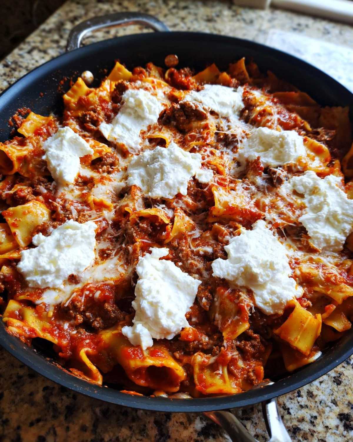 Close-up of finished skillet lasagna topped with large dollops of ricotta cheese and melted mozzarella.