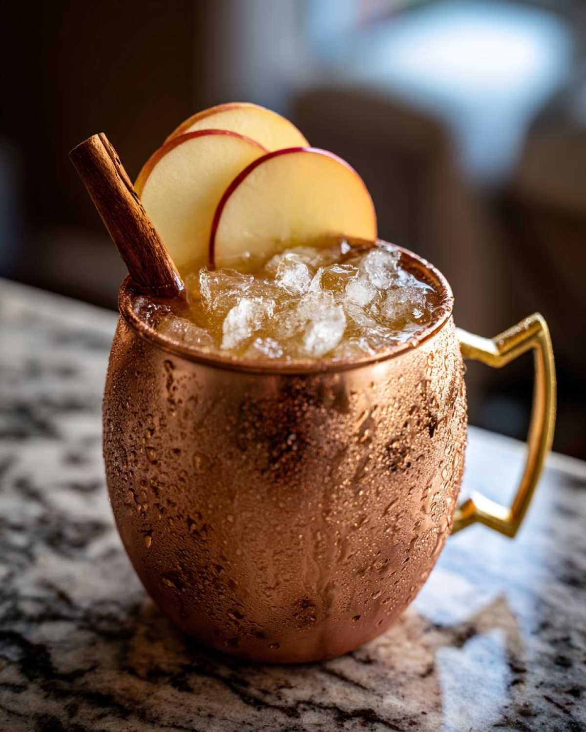 A condensation-covered copper mug filled with ice and an apple cider moscow mule, garnished with apple slices and a cinnamon stick.