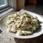 A bowl of creamy cottage cheese chicken salad topped with fresh dill and black pepper.