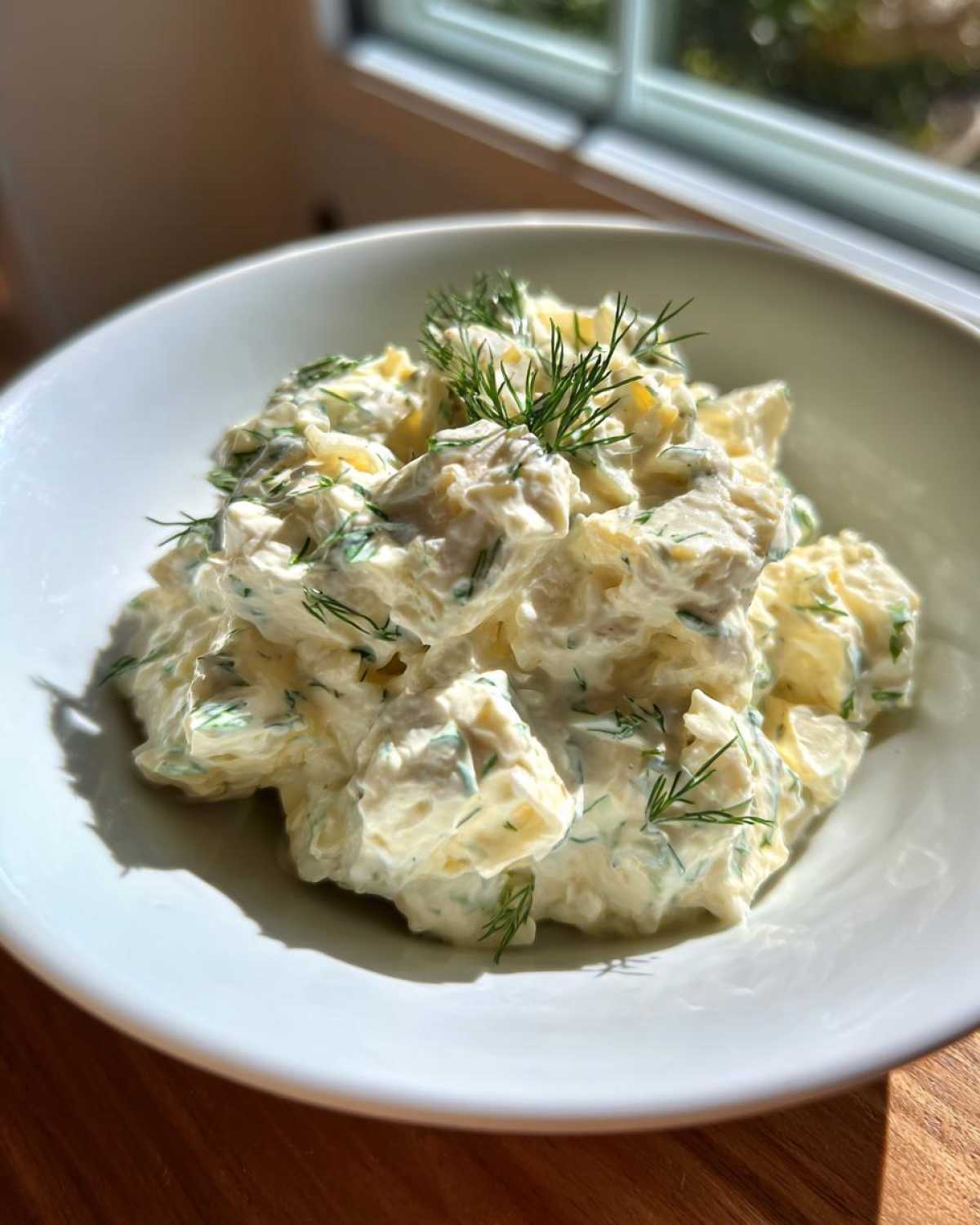 Close-up of creamy cottage cheese chicken salad mixed with herbs and topped with fresh dill.