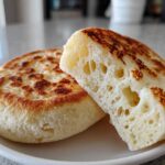 Close-up of a fluffy homemade english muffin, cut in half to show the signature nooks and crannies texture.