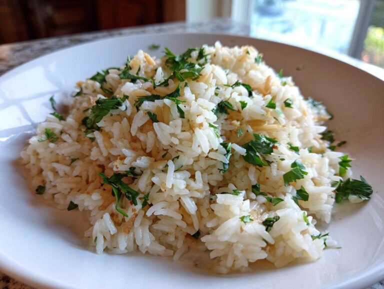 A close-up of fluffy rice pilaf topped with fresh green parsley in a white bowl.