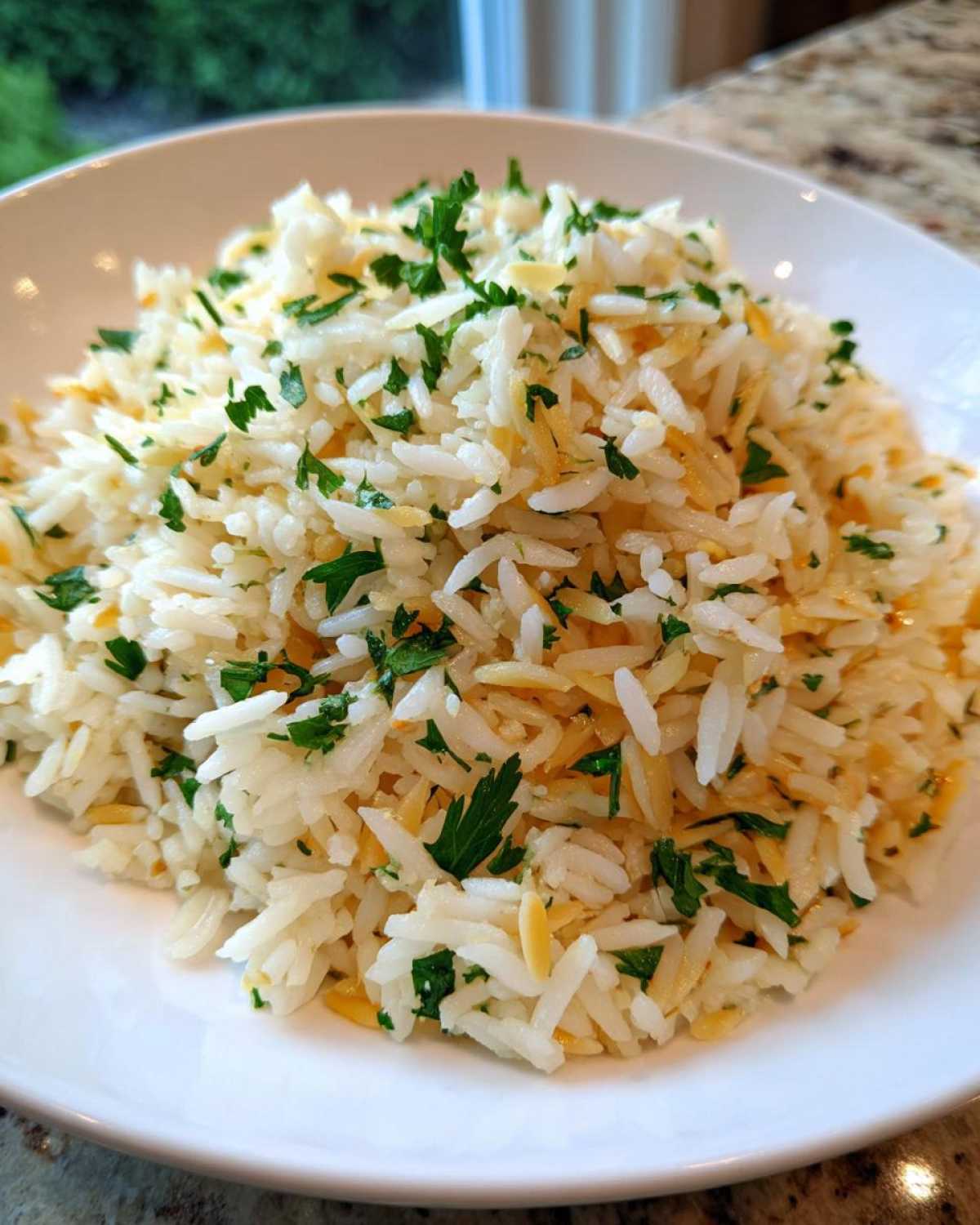 Close-up of fluffy rice pilaf mixed with toasted orzo and garnished generously with fresh chopped parsley.