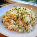 Close-up of fluffy rice pilaf mixed with toasted vermicelli and topped with fresh chopped parsley.