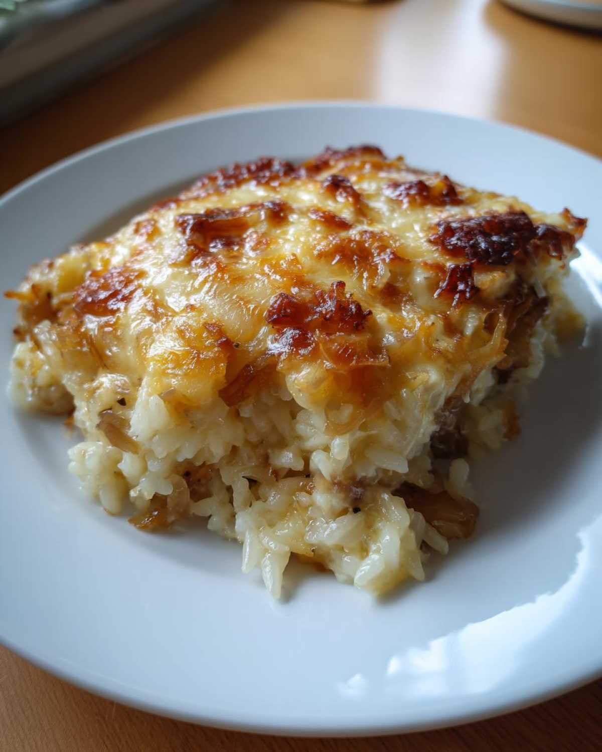 A close-up of a serving of french onion butter rice topped with melted, browned cheese.