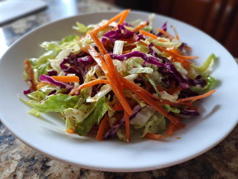 Close-up of a vibrant cabbage salad featuring shredded green cabbage, red cabbage, and bright julienned carrots.