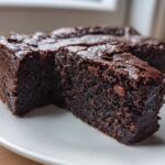 Close-up of two fudgy sweet potato brownies slices showing their dense, dark chocolate texture on a white plate.