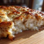 A cross-section view of a juicy Garlic Parmesan Chicken Bake showing melted, browned cheese topping over tender chicken.