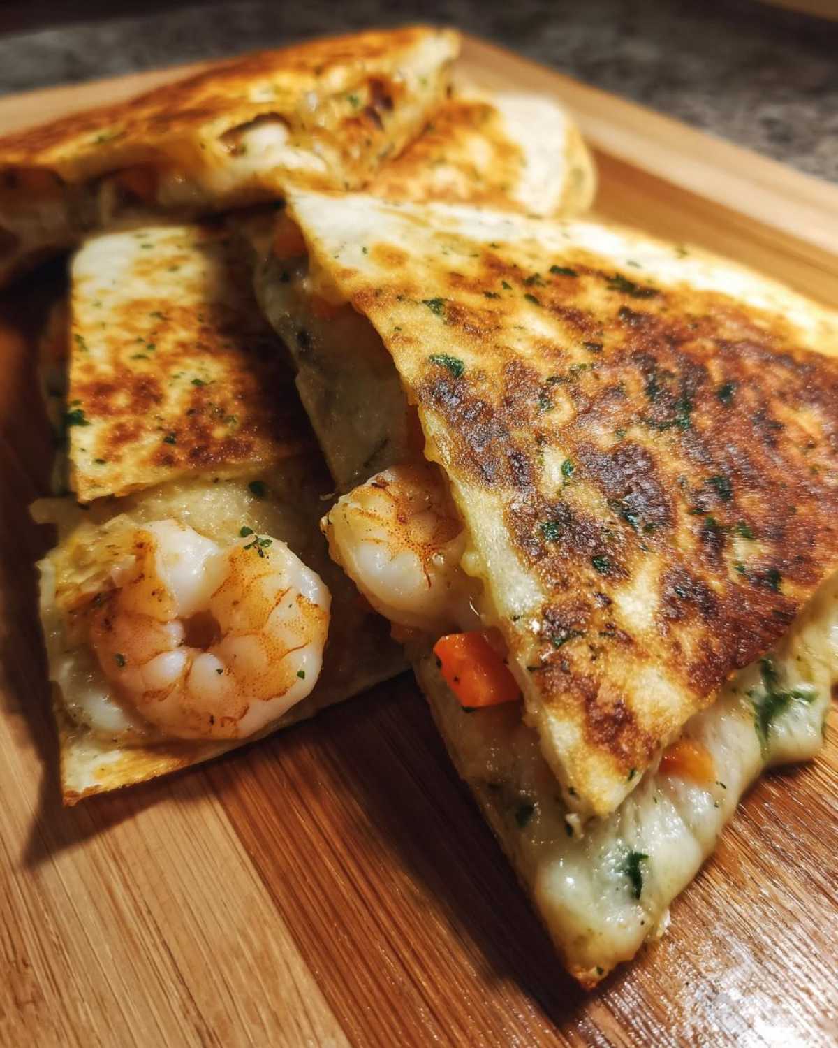 Close-up of golden-brown, grilled shrimp quesadilla slices showing melted cheese and visible shrimp pieces.