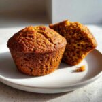 Close-up of two delicious honey bran muffins, one whole and one broken open to show the texture.
