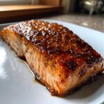 Close-up of a perfectly cooked salmon fillet coated in a thick, shiny honey garlic glaze.