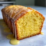 Close-up of a freshly baked lemon pound cake loaf with a thick, sweet glaze dripping down the sides.