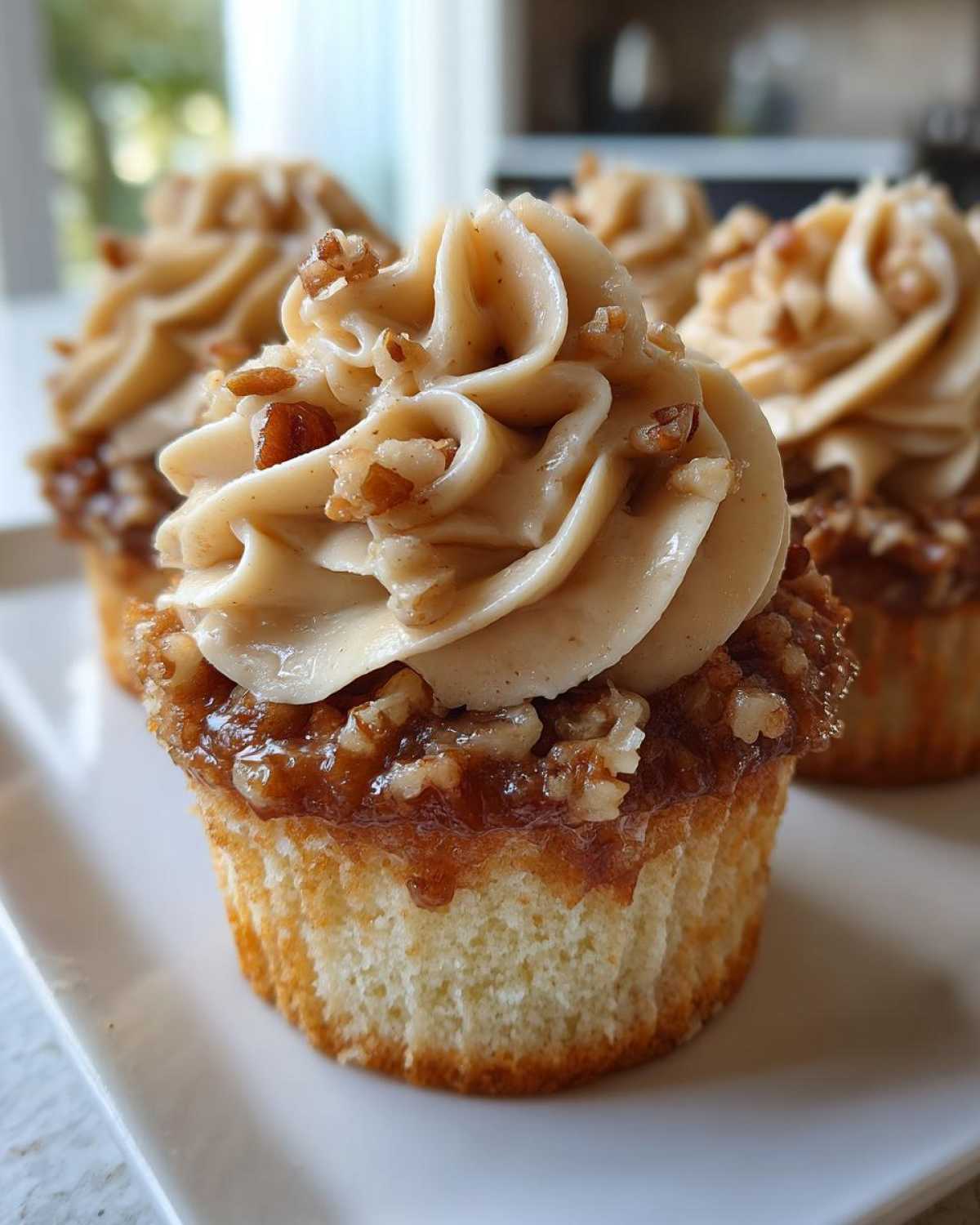 Close-up of a delicious pecan pie cupcake topped with caramel pecan filling and swirled brown sugar frosting.