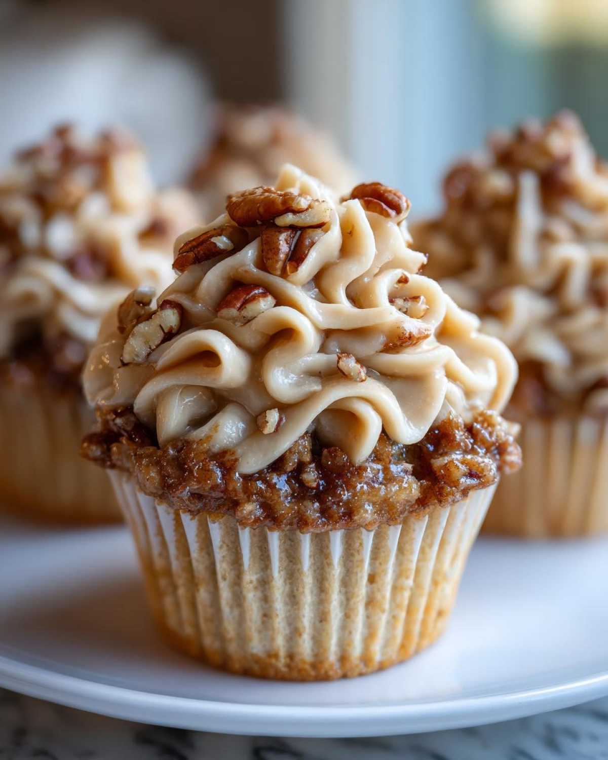 Close-up of one of the amazing pecan pie cupcakes topped with caramel-colored frosting and chopped pecans.