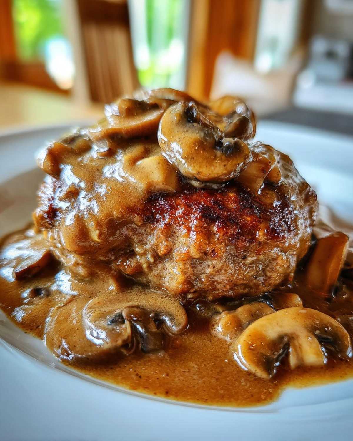 Close-up of a perfectly seared Salisbury steak smothered in rich brown mushroom gravy.
