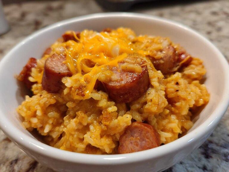 Shocking 35-Minute Sausage and Rice Magic Close-up of a white bowl filled with cheesy sausage and rice, topped with melted cheddar.