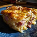 Close-up of a rich, creamy slice of scalloped potatoes and ham with a golden, cheesy crust.
