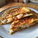 Close-up of a perfectly grilled shrimp quesadilla, cut in half, showing melted cheese and plump shrimp filling.