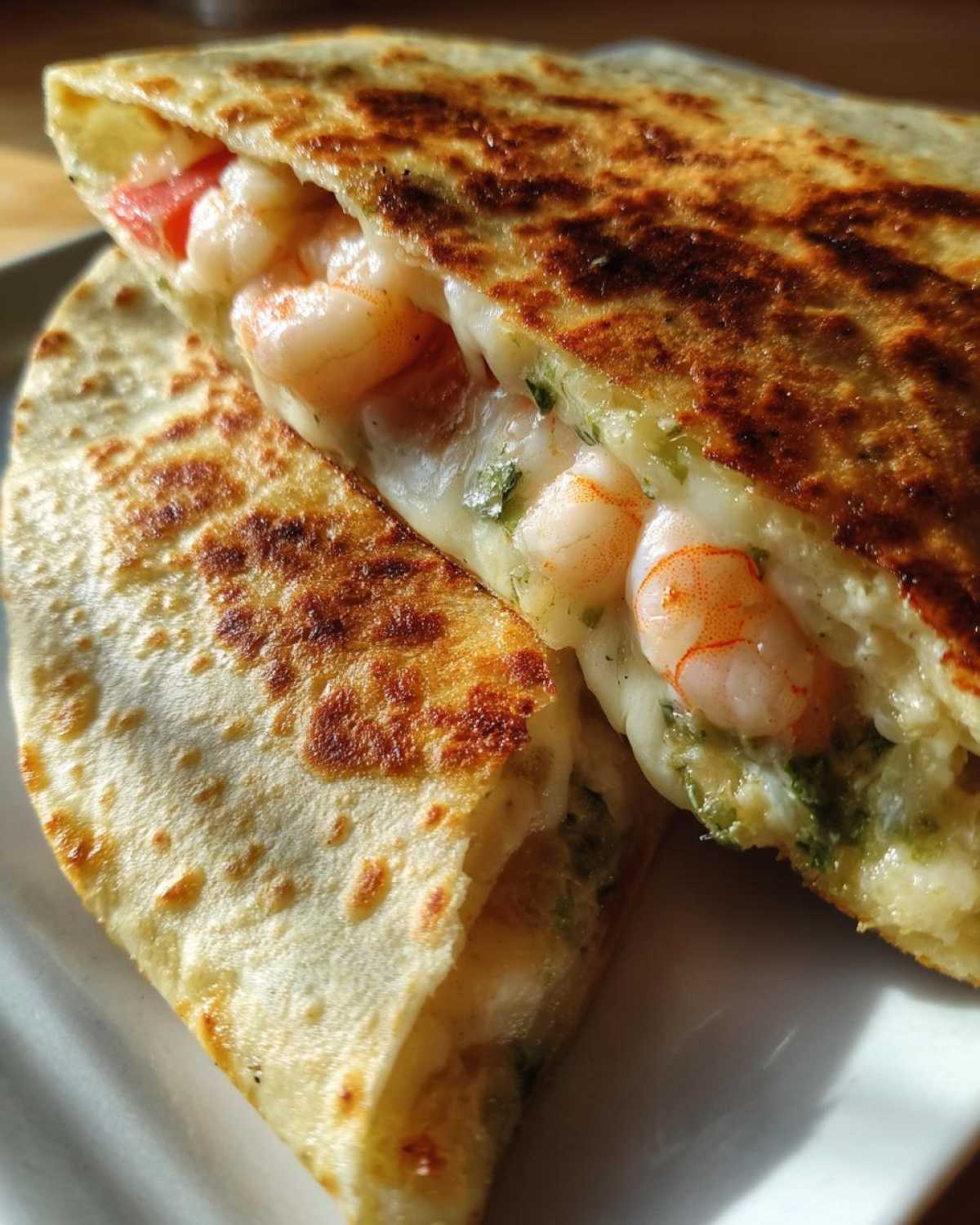Close-up of a perfectly grilled shrimp quesadilla cut in half, showing melted cheese and plump shrimp inside.