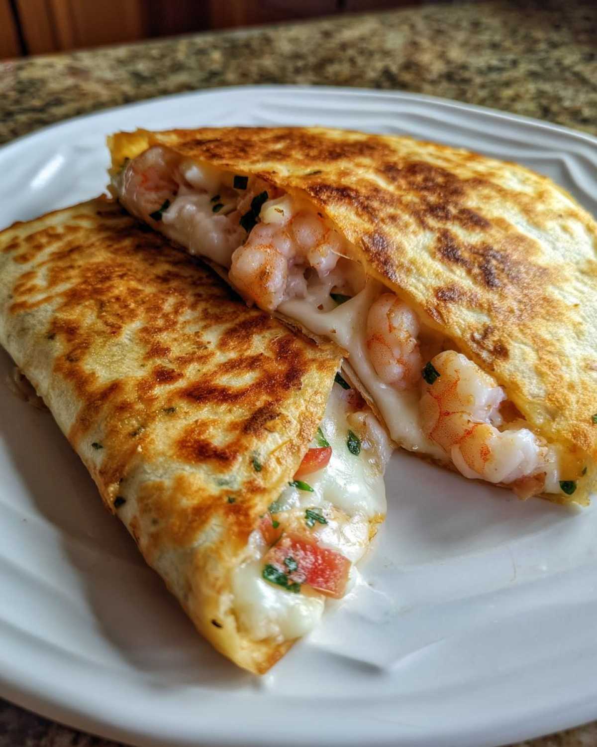 Two halves of a perfectly grilled shrimp quesadilla showing melted cheese and pink shrimp filling.