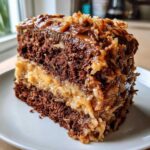 Close-up of a decadent slice of german chocolate cake with thick coconut-pecan frosting layers.