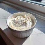 A small white bowl filled with thick, white, perfectly piped sugar cookie icing that hardens.