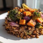 Close-up of a portion of veggie lentil salad topped with roasted sweet potatoes, broccoli, and red onion.