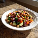 A colorful serving of fresh bean salad featuring chickpeas, diced cucumber, red onion, and bell pepper in a white bowl.