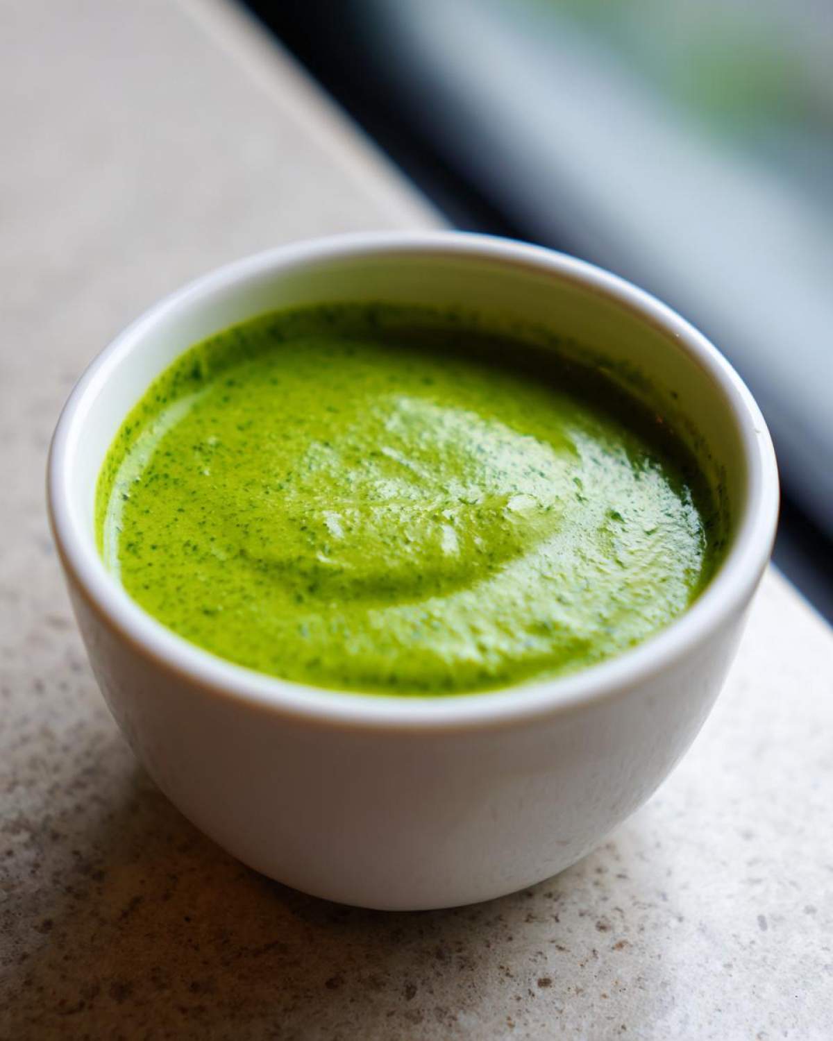 Close-up of bright green, freshly blended cilantro lime sauce served in a small white dipping bowl.