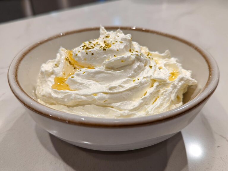 A bowl of fluffy, white whipped feta dip topped with honey and herbs.