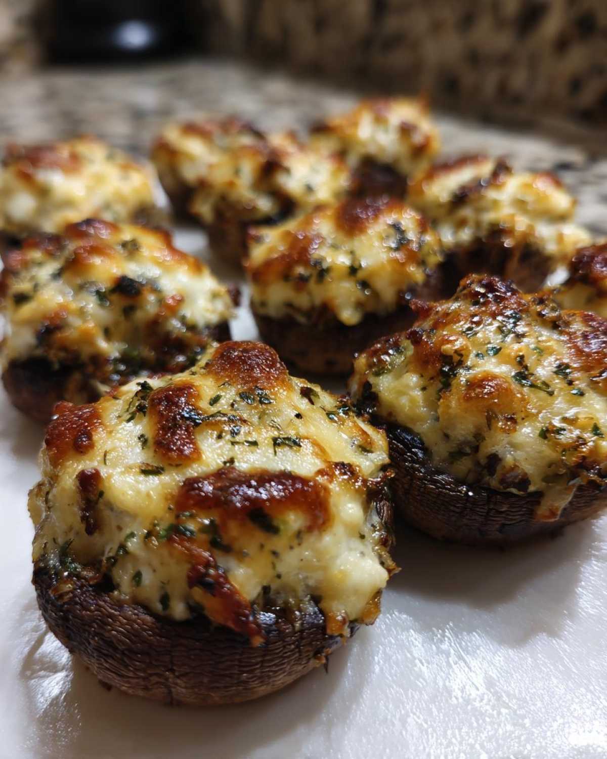 Close-up of several golden brown Air Fryer Cheddar Stuffed Mushrooms with melted, bubbly cheese topping.