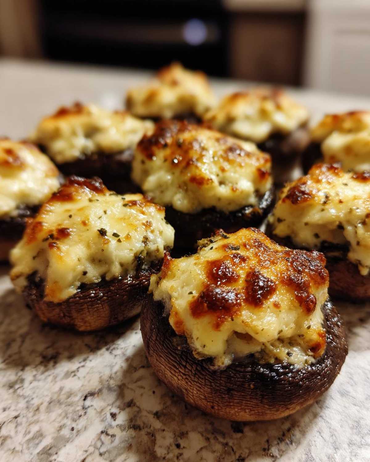 Close-up of several Air Fryer Cheddar Stuffed Mushrooms with golden brown, melted cheese topping.