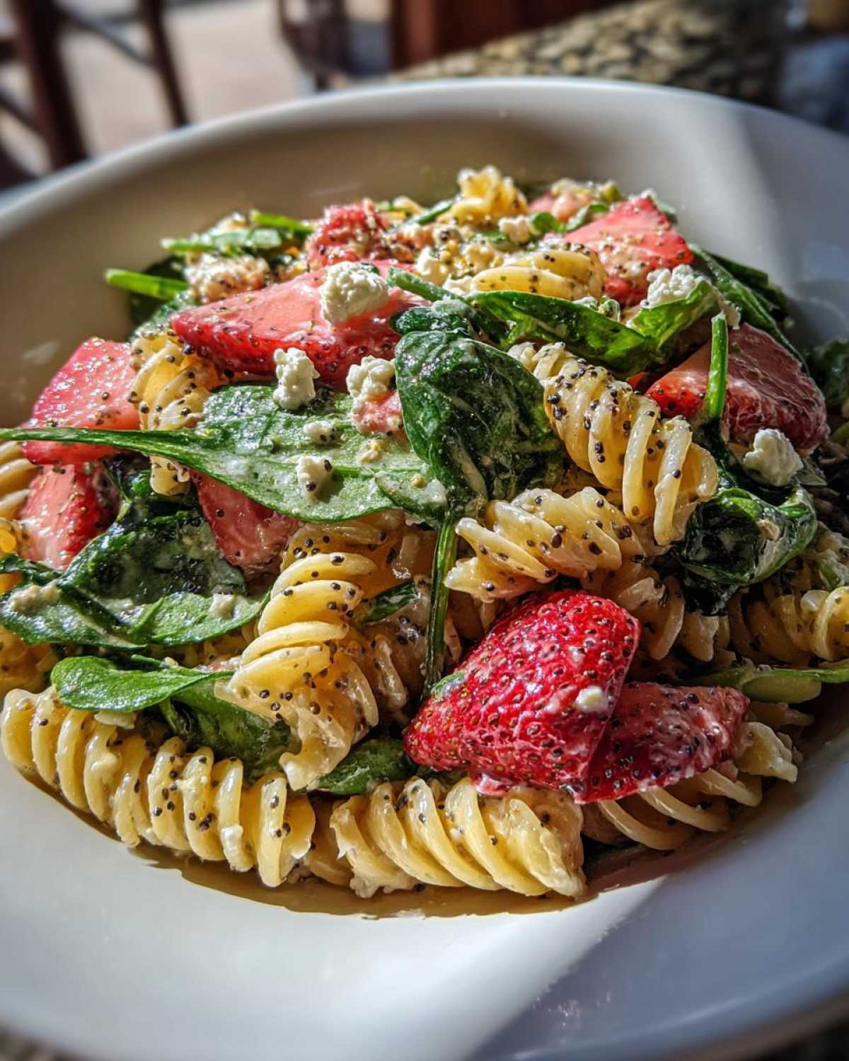 A close-up of Easy Strawberry Spinach Pasta Salad with Feta, featuring rotini pasta, fresh strawberries, spinach, and crumbled feta.