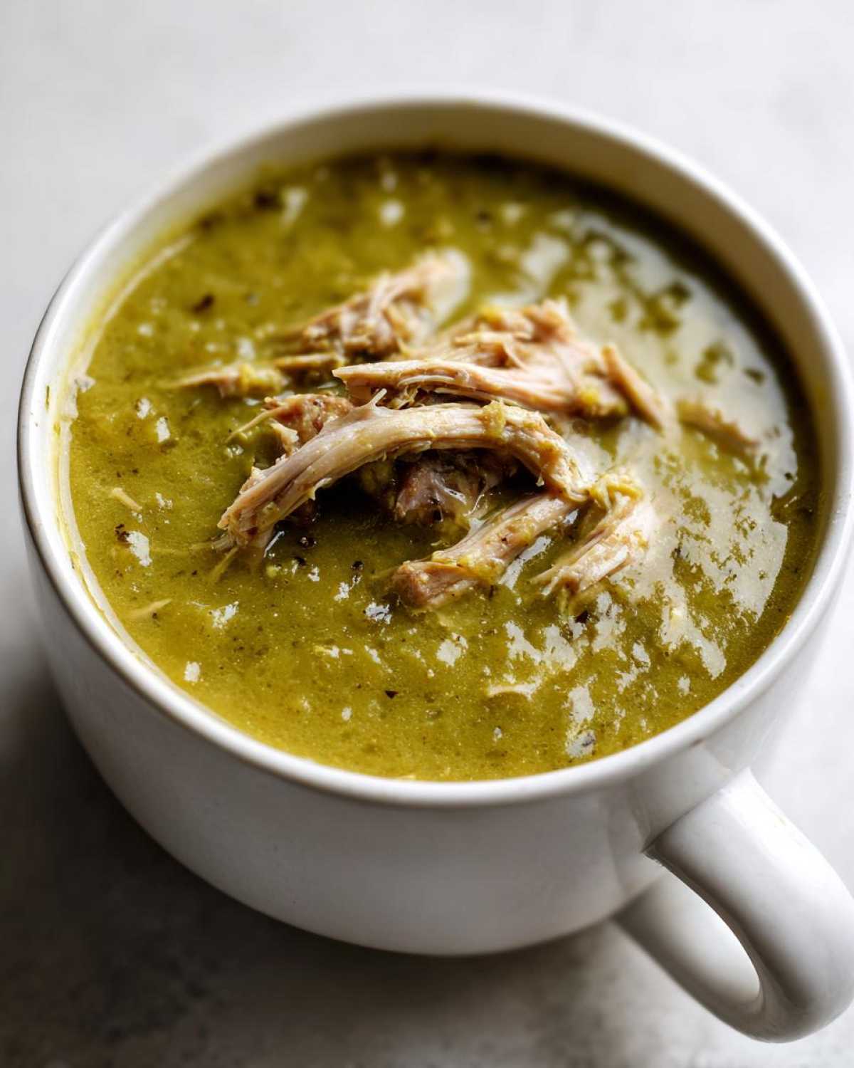 Close-up of thick, green Instant Pot Split Pea Soup topped with shredded smoked turkey meat.
