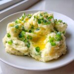 A serving of creamy Irish Champ mashed potatoes topped with melted butter and fresh chopped scallions.