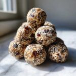 A close-up stack of No-Bake Lemon Blueberry Energy Bites made with oats and dried fruit.