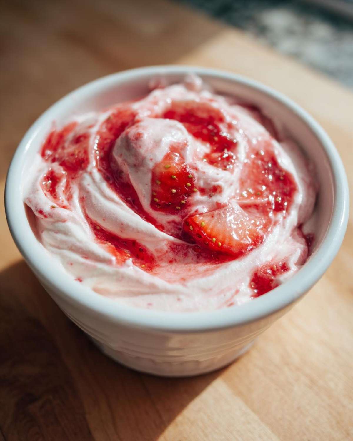 Close-up of a white bowl filled with No-Bake Strawberry Cheesecake Dip topped with strawberry swirl.